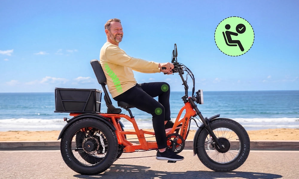 A man riding a Meetone electric trike on a beach road, showcasing the semi-recumbent seating position with ergonomic back support.